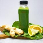A refreshing green juice displayed with ginger and citrus slices, promoting wellness.