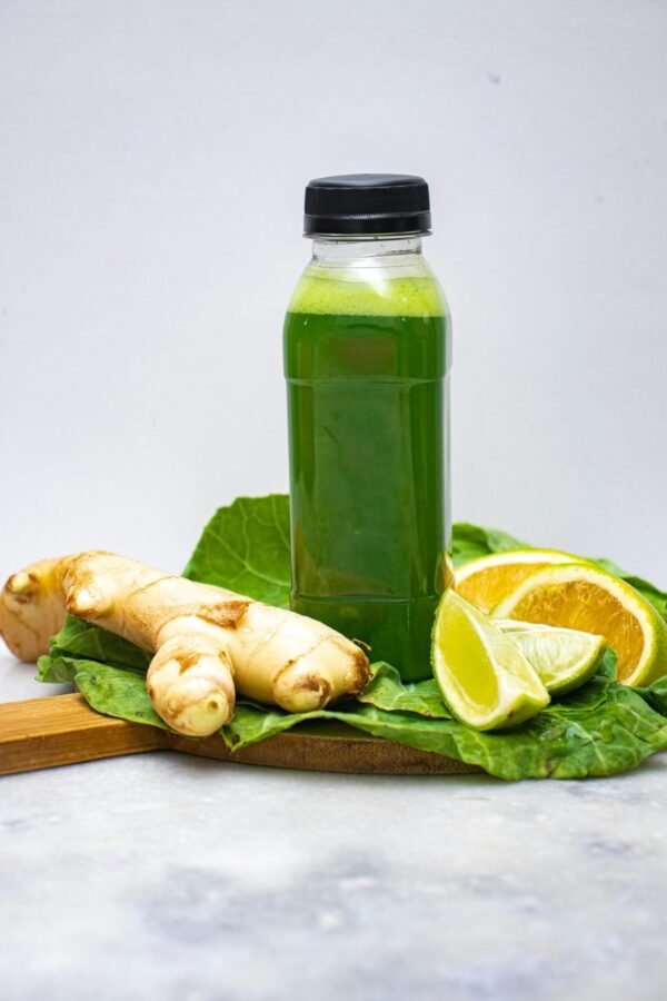 A refreshing green juice displayed with ginger and citrus slices, promoting wellness.